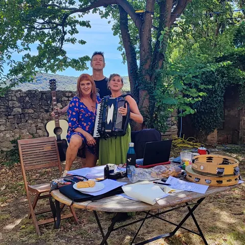 Le trio en plein air, accordéon et guitare, derrière une table