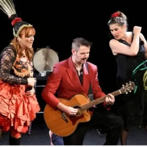Le trio en costumes de scène : plumes, guitare et tambourin