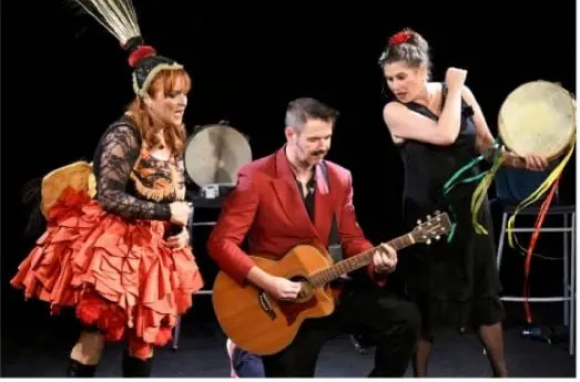 Le trio en costumes de scène : plumes, guitare et tambourin