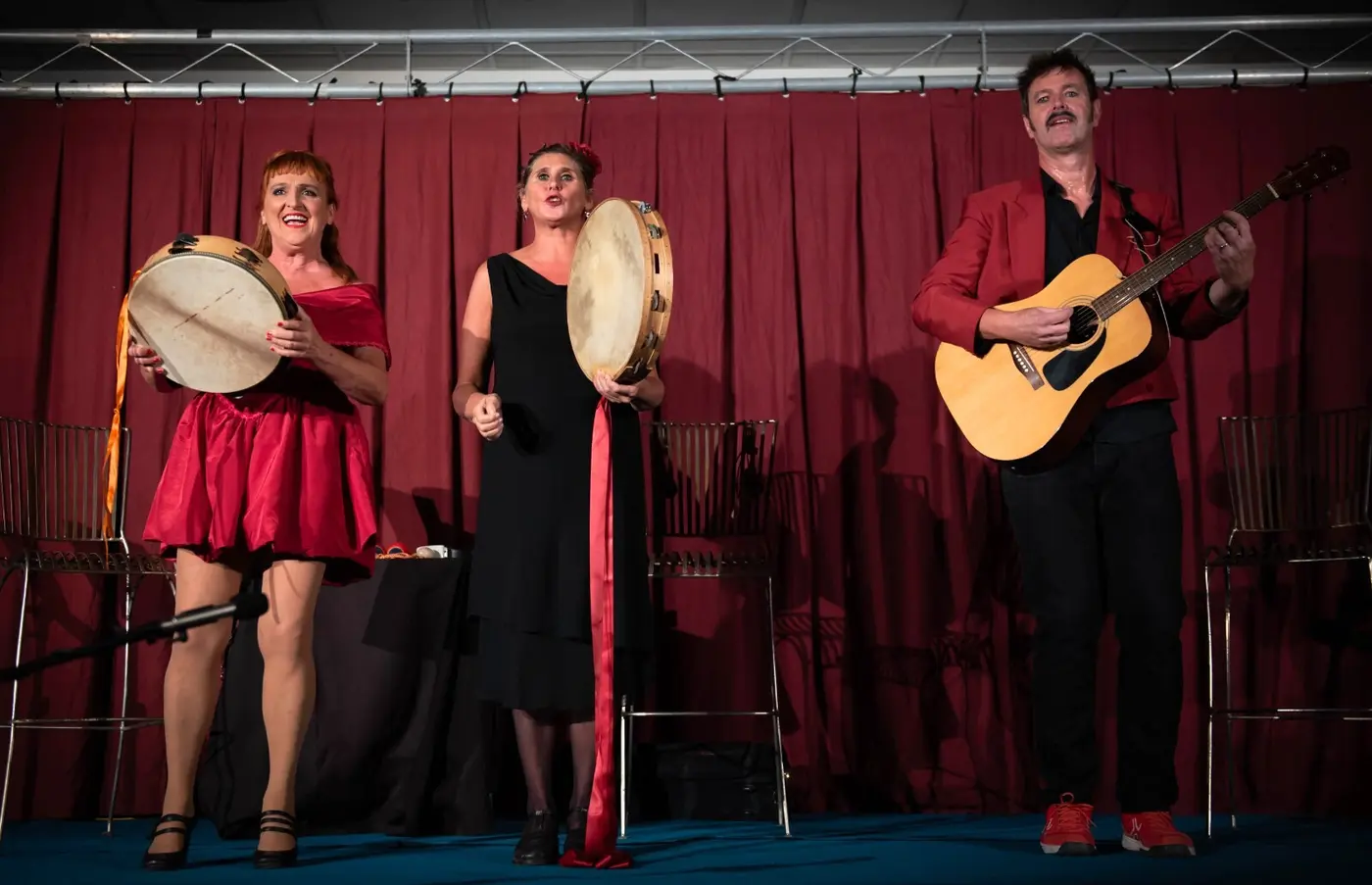 Deux tambourins et une guitare devant le rideau rouge